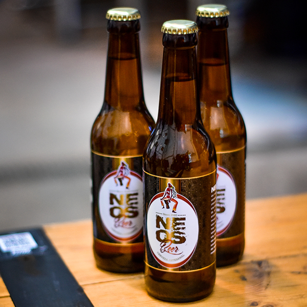 Botellas de cerveza NEOS en una mesa de madera, con etiquetas distintivas y un diseño atractivo, ideales para los amantes de la cerveza artesanal.